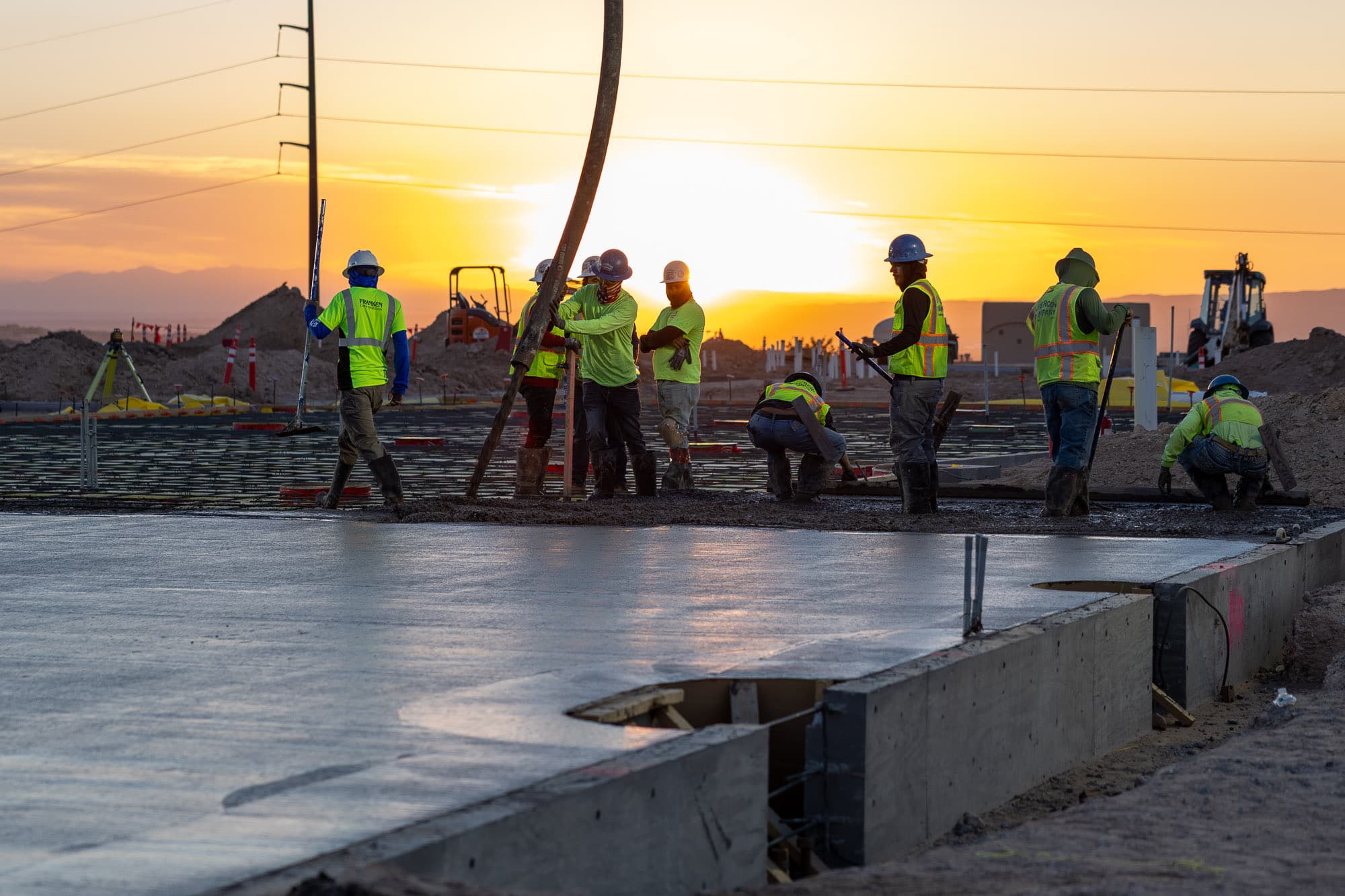 Concrete crew finishing a slab at sunset