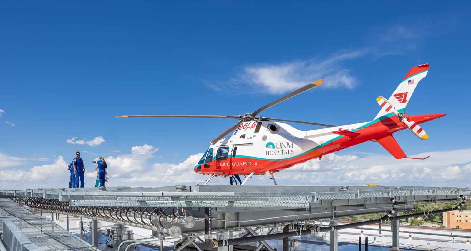 Red and white air ambulance on the rooftop helipad, crew beside it